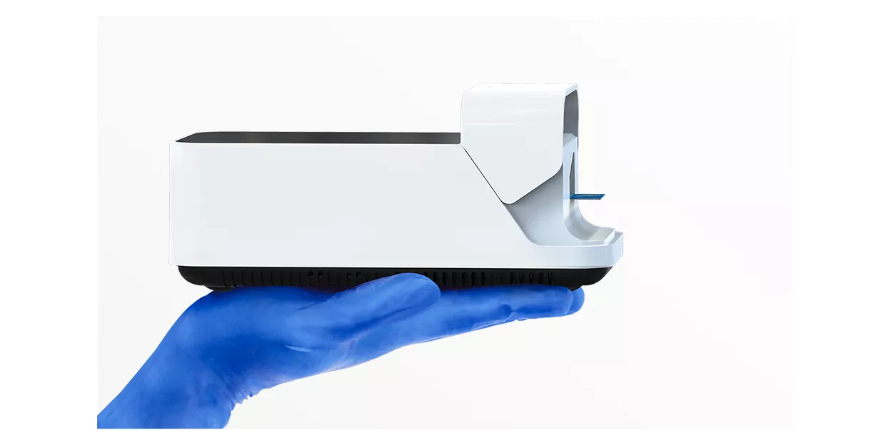 Instrumento LumiraDx sostenido sobre una mano enguantada